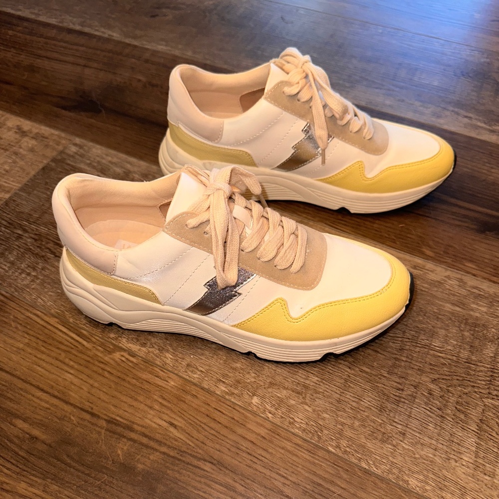 Yellow and cream colored tennis shoes with silver lightning bolt